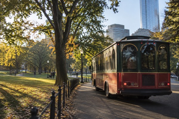 Trolley passing a historic Boston burying ground at dusk