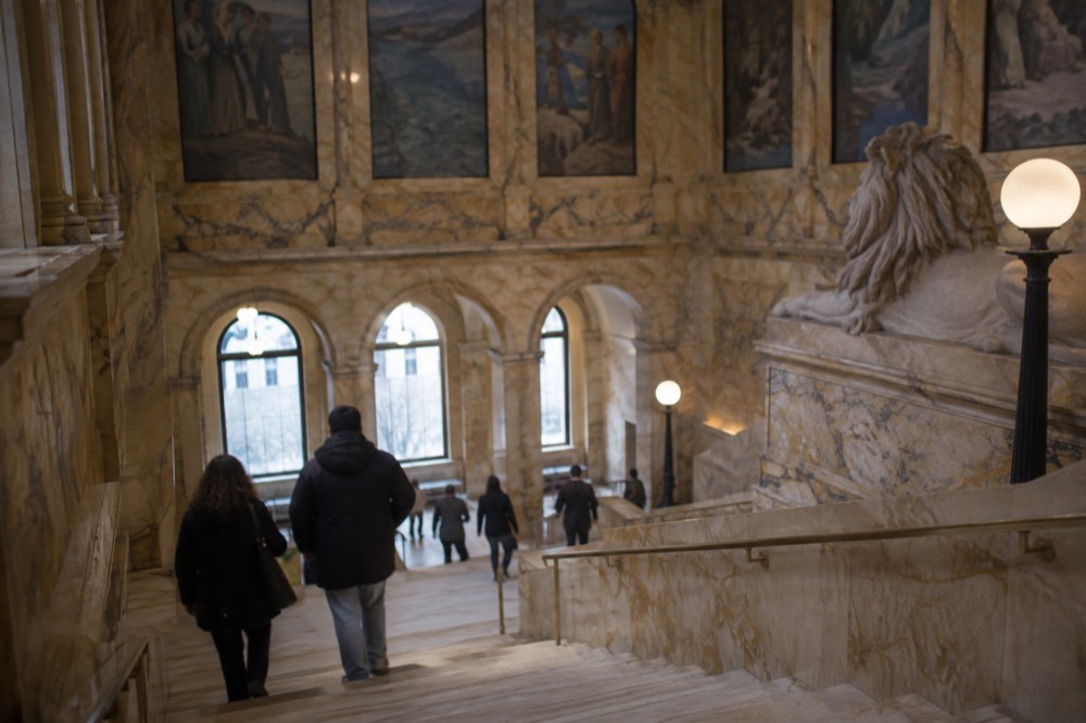Visitors walking through the grand staircase hall of the Boston Public Library's McKim building