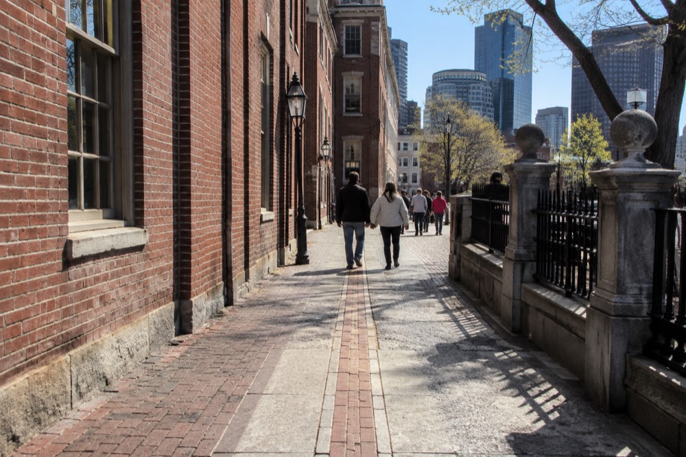 Visitors walking along a red brick Freedom Trail line past historic Boston buildings