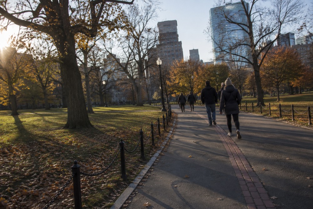 Visitors walking along a red brick line on a historic Boston sidewalk