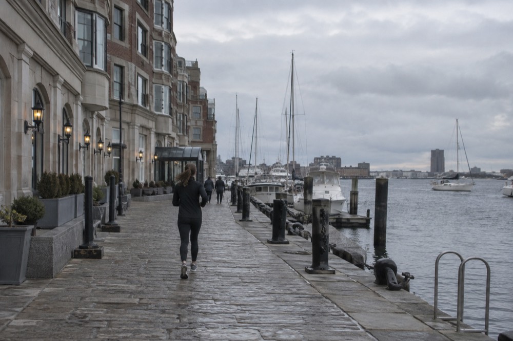 A waterfront hotel building beside a harbor with boats docked along the wharf