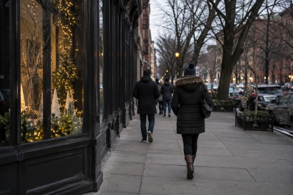 Visitors walking past a decorated storefront in downtown Boston on a winter evening