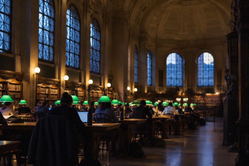 Readers working at wooden tables in Bates Hall, the Boston Public Library's grand reading room