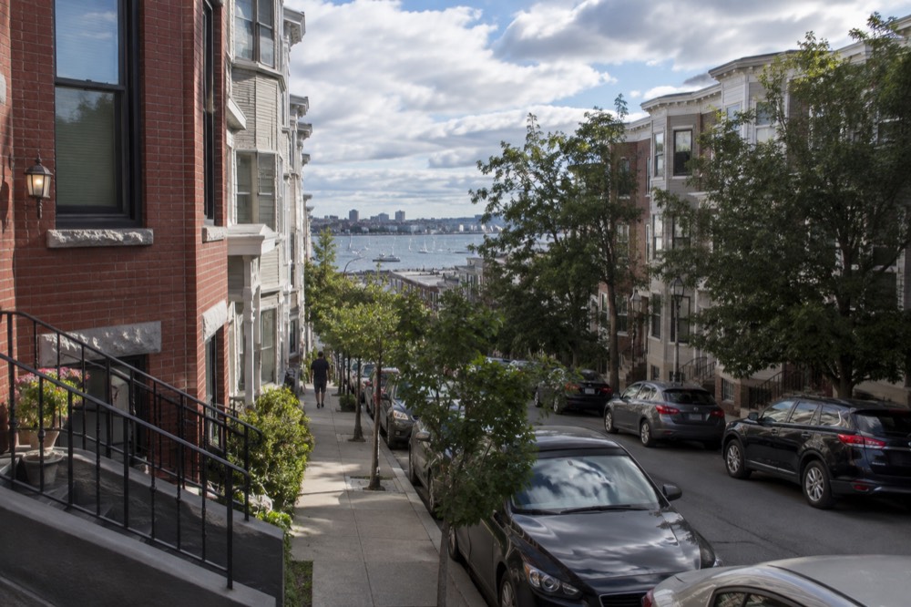 Rowhouses on a quiet South Boston street with parked cars and leafy trees