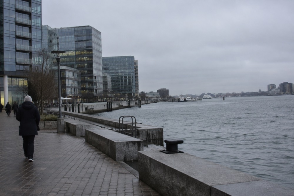 Modern glass buildings along the South Boston waterfront with the harbor behind them