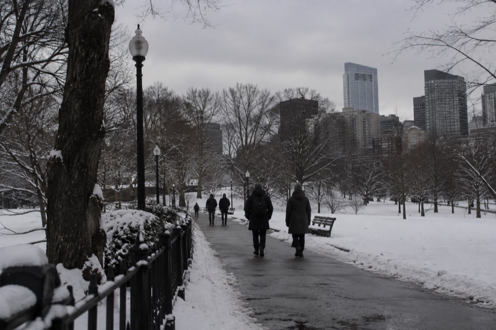 A snow-covered Boston street with brick rowhouses and cleared sidewalks