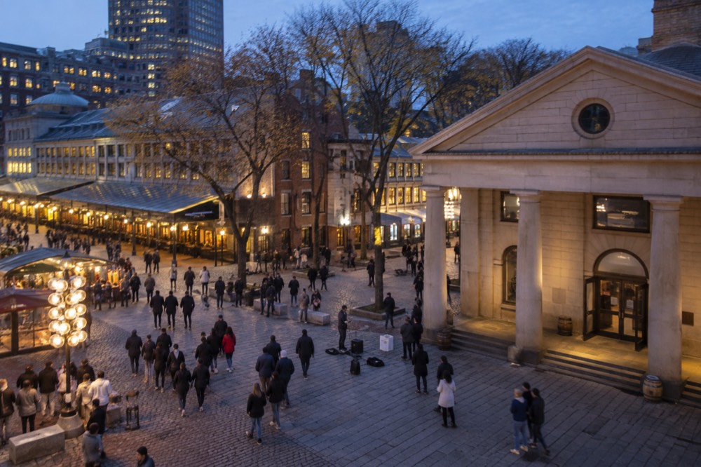 Crowds walking past street performers outside Faneuil Hall in downtown Boston on a sunny afternoon