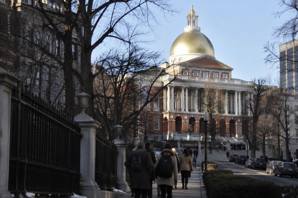 Tourists walking past the gilded dome of the Massachusetts State House on Beacon Street
