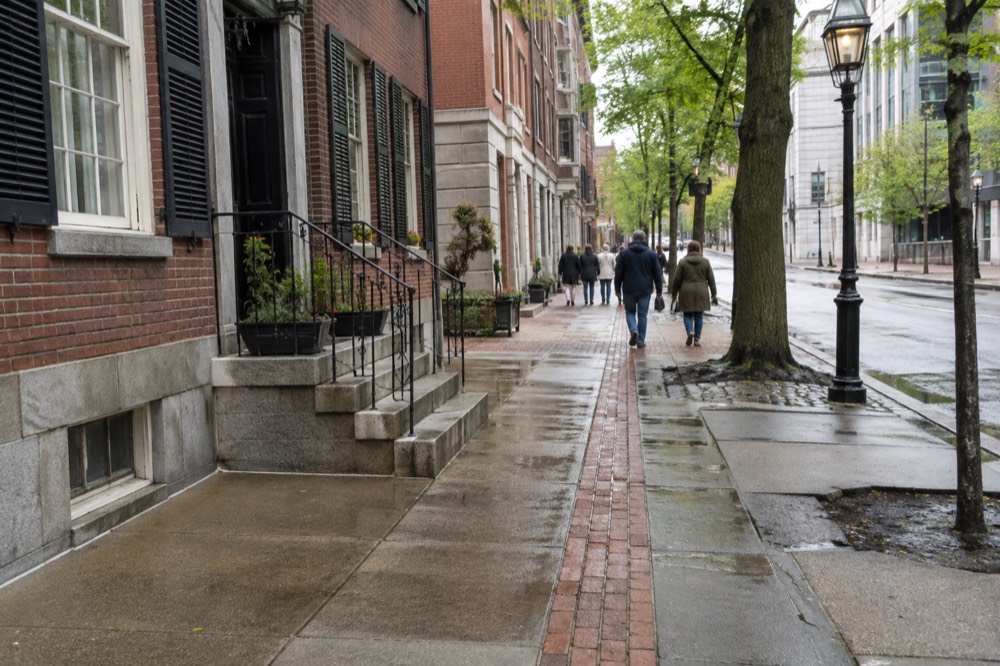 Visitors walking the red brick line of the Freedom Trail past historic downtown buildings