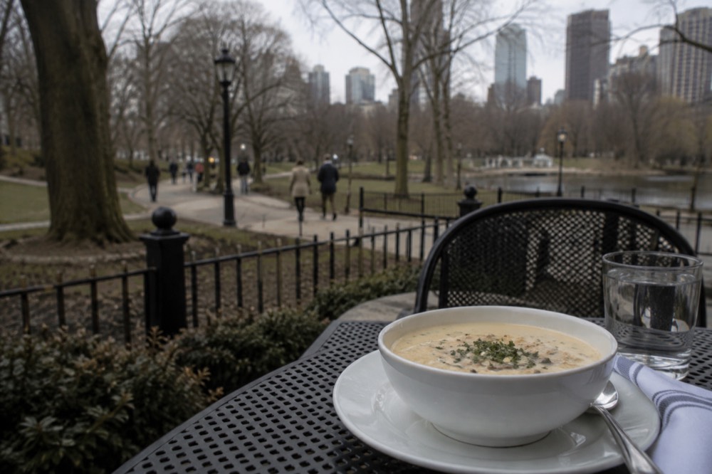 A bowl of New England clam chowder topped with herbs on a restaurant table