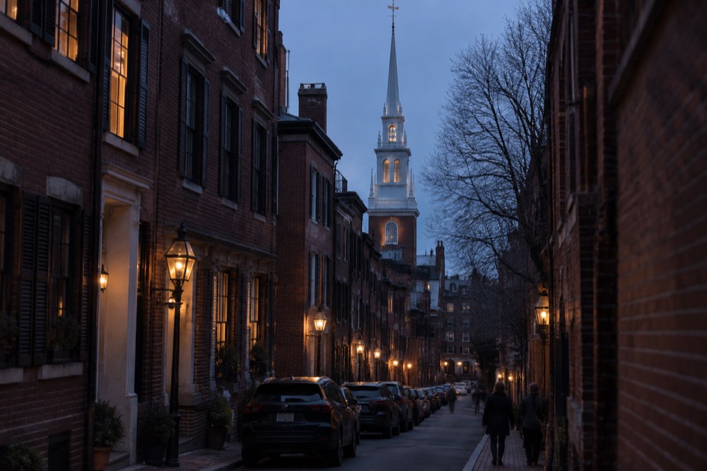 Red brick row houses on a narrow Boston street with the Old North Church spire rising above the neighborhood