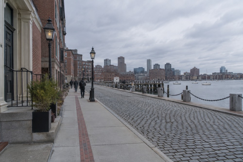A red brick Freedom Trail marker line running along a narrow old Boston sidewalk