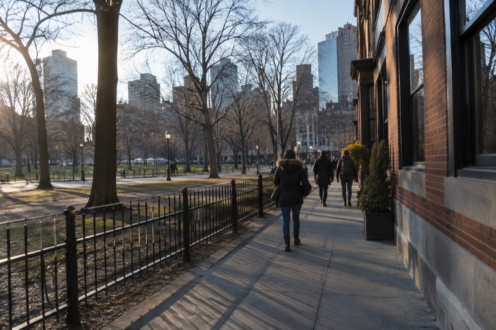 People walking along a busy Boston sidewalk near brick storefronts