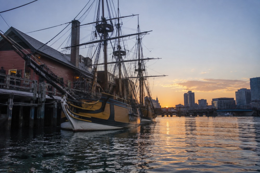 Wooden tall ships moored at a Boston harbor wharf at dusk
