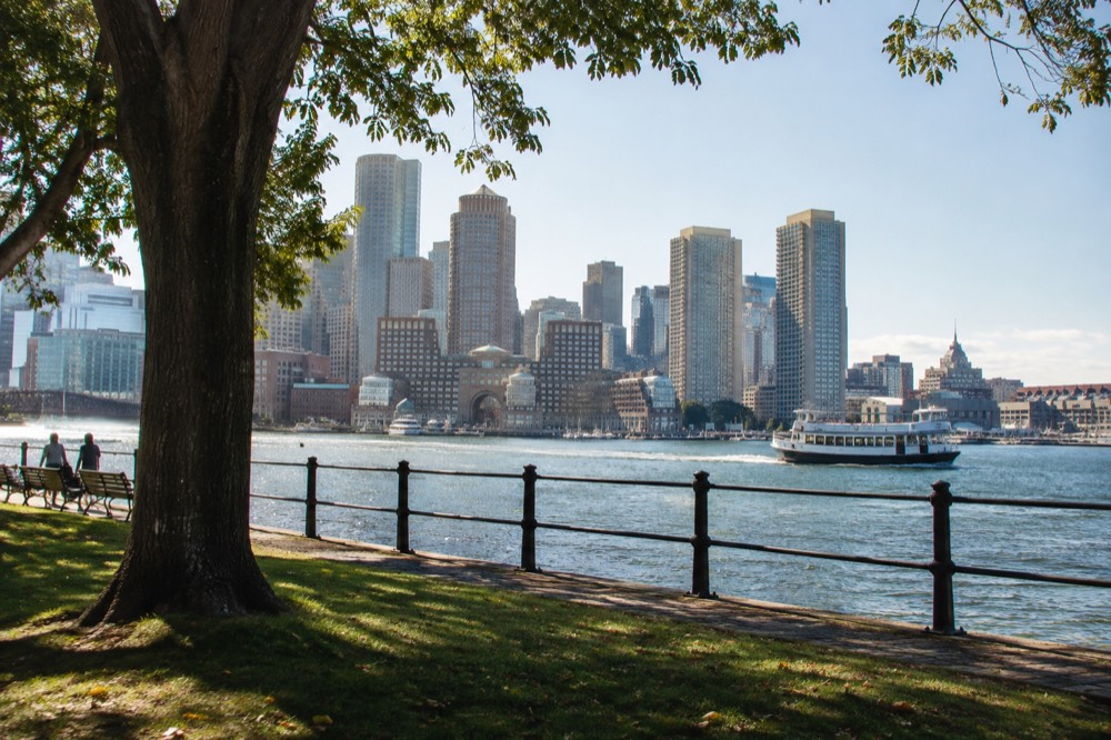 A sightseeing boat passing Boston harborfront buildings under a clear sky