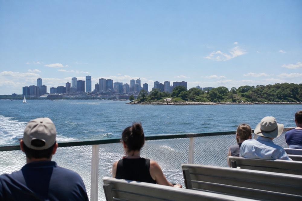 A ferry crossing Boston Harbor toward green islands on a clear summer day