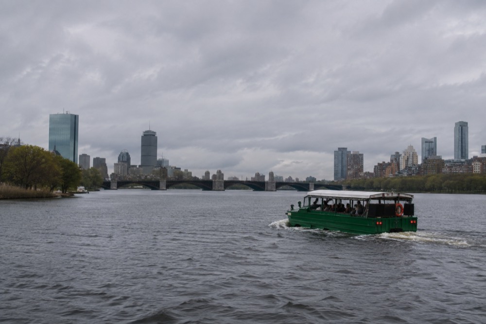 An amphibious duck boat cruising on the Charles River with the Boston and Cambridge skylines on either bank