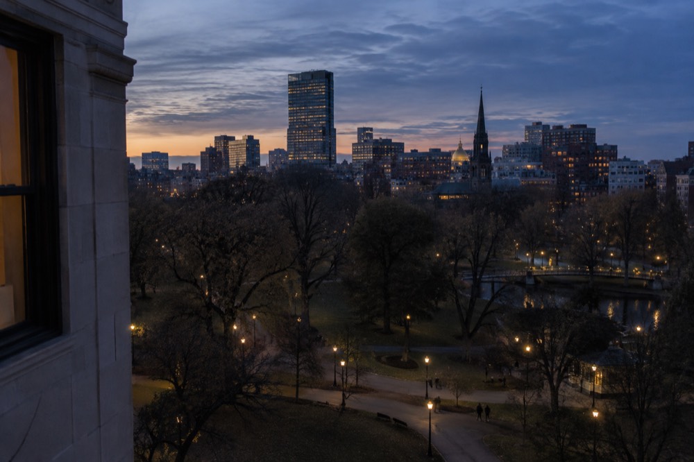 Evening view of Boston rooftops and a church spire from a hotel window