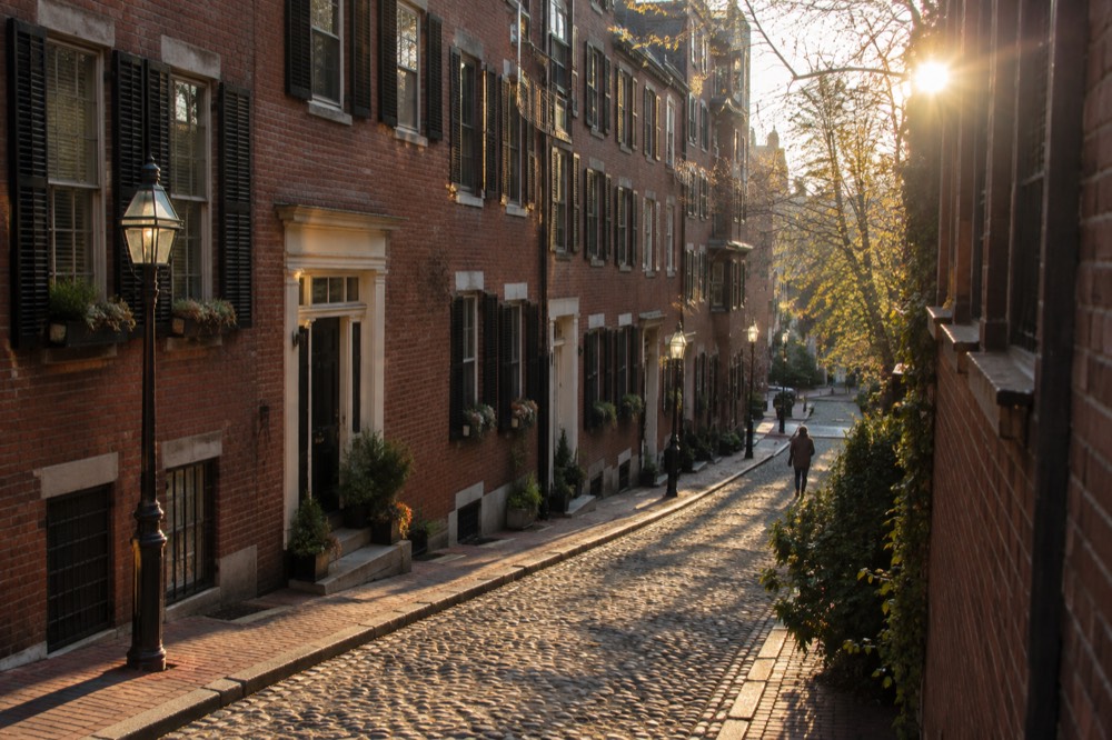 A red-brick street on Beacon Hill curving past a colonial-era row house
