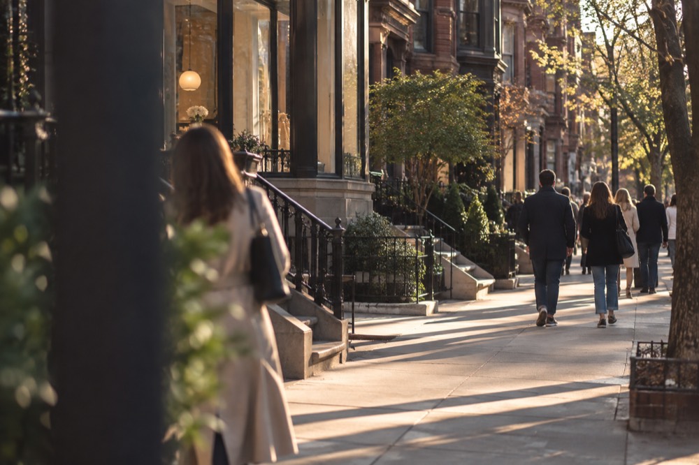 Shoppers walking past boutiques and cafes on Newbury Street on a sunny afternoon