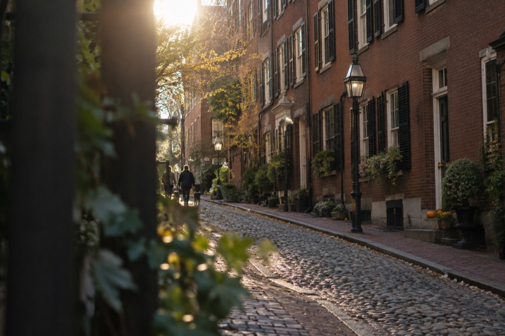 Row of brick row houses with black shutters on a quiet Beacon Hill street