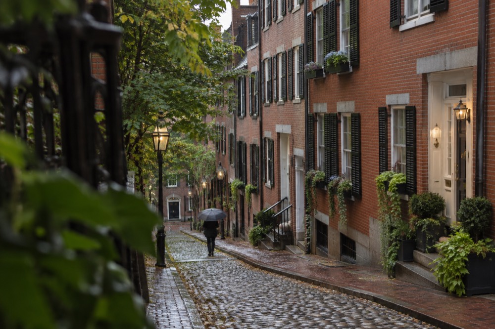 Red brick row houses with brass door knockers and window boxes on a Beacon Hill street