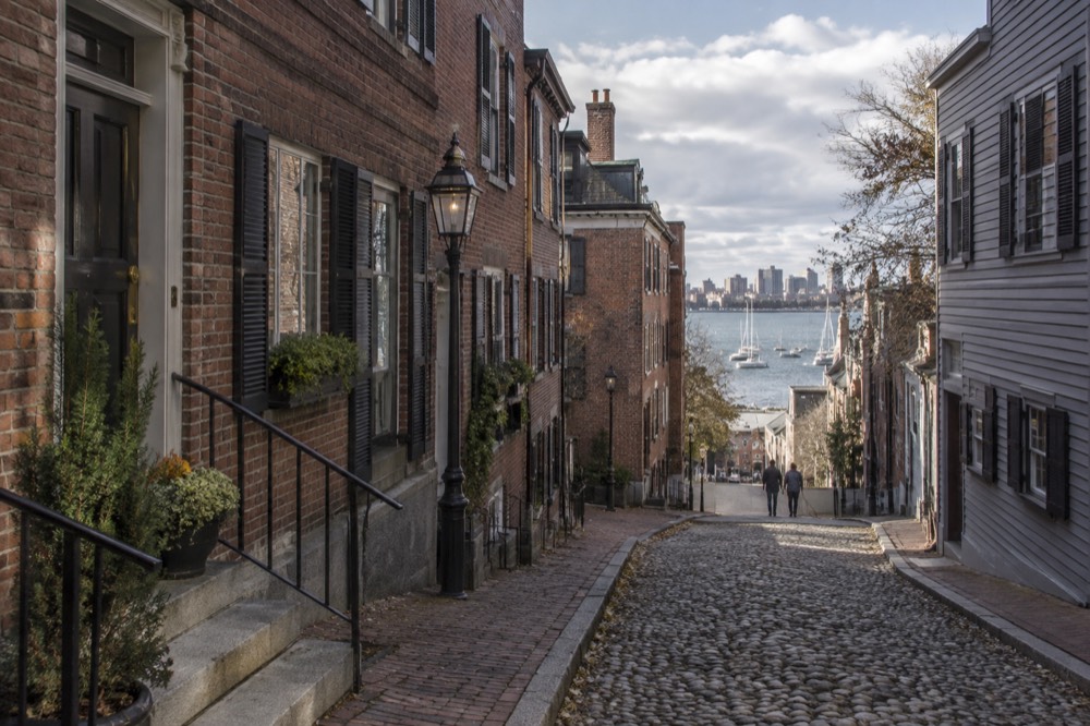 Narrow cobblestone street lined with old brick buildings and small shopfronts