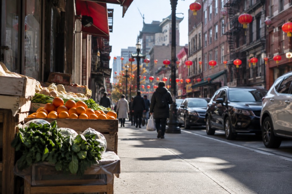 A busy Chinatown street with red lanterns strung overhead and restaurant signs on both sides