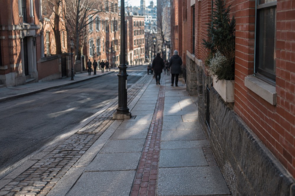 A red-brick Freedom Trail line embedded in a downtown Boston sidewalk