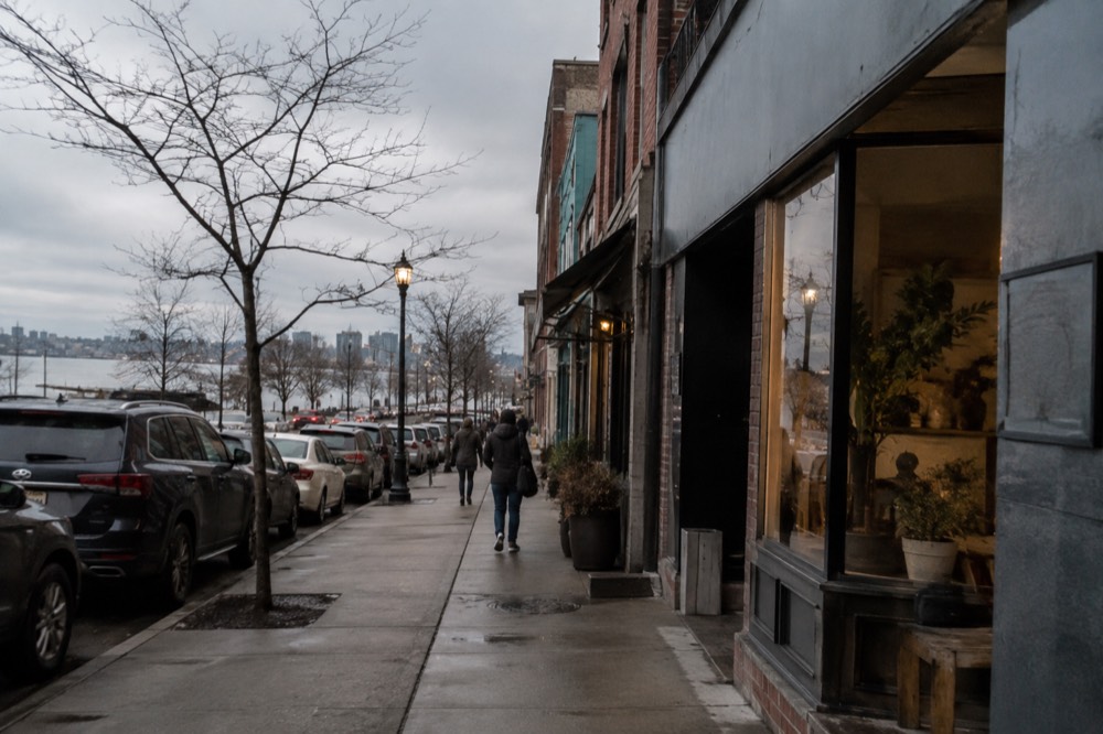 People walking past storefronts on a busy neighborhood commercial street