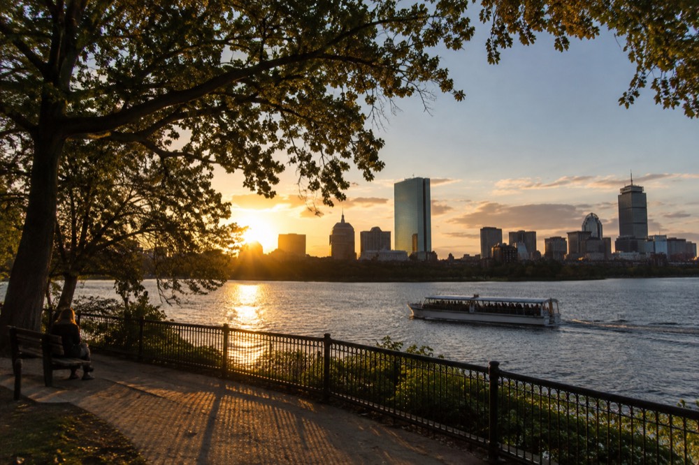 A sightseeing boat passing the Boston skyline at sunset