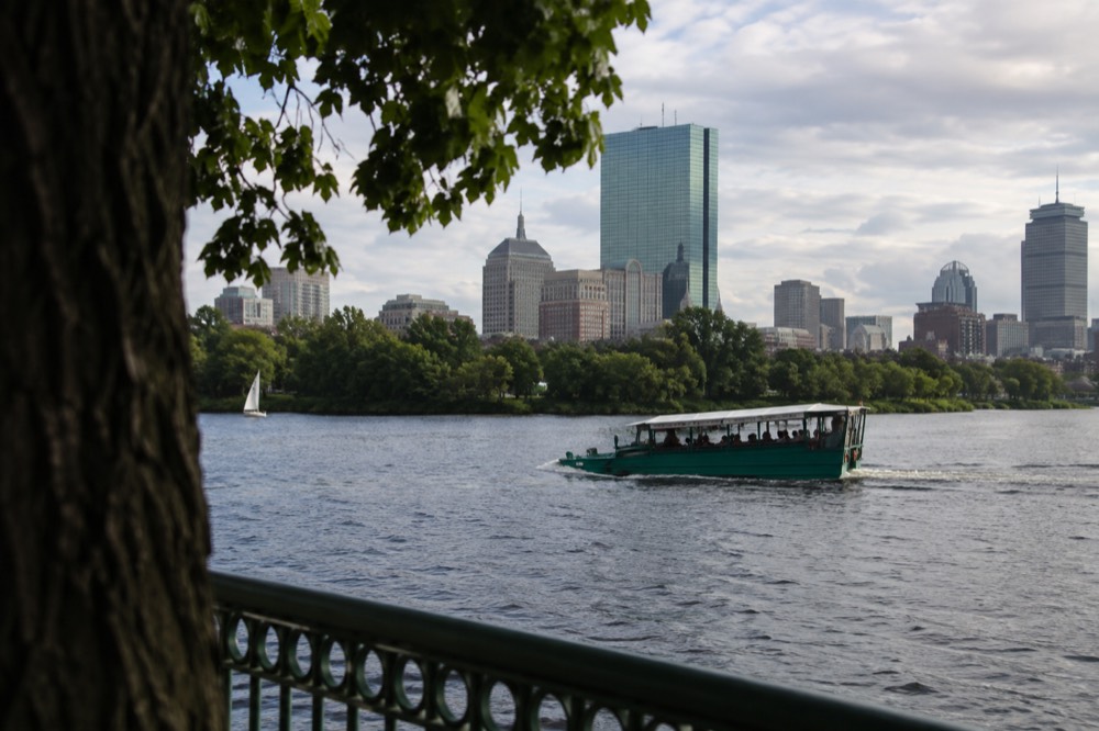 An amphibious duck boat cruising on the Charles River with the Boston skyline behind