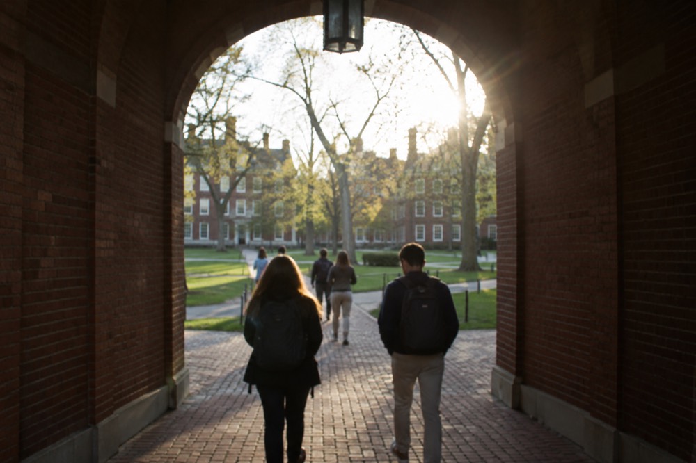 Students walking through a brick archway into Harvard Yard