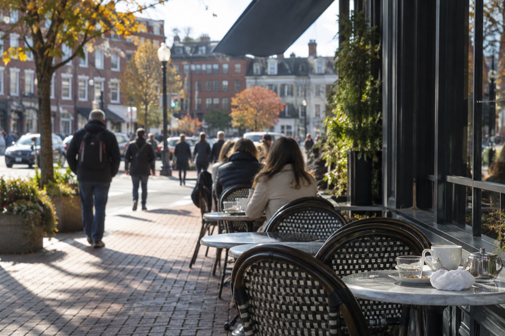 Outdoor cafe tables along a busy Cambridge sidewalk at lunchtime