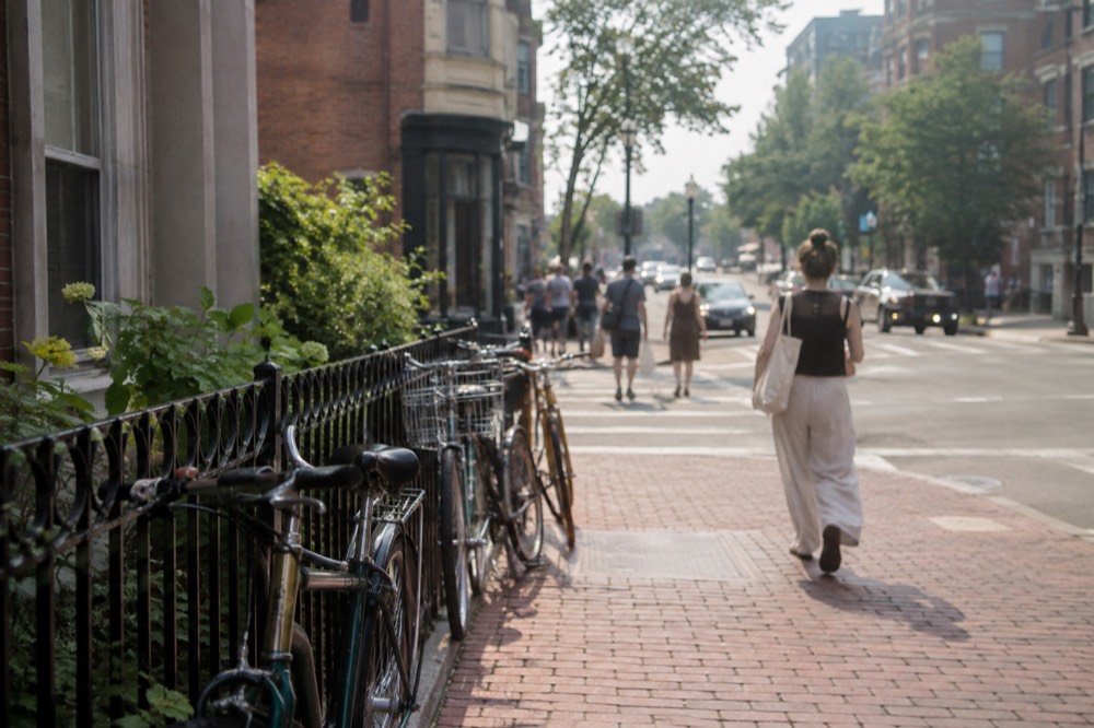Brick sidewalk in Cambridge with bicycles leaning against a railing