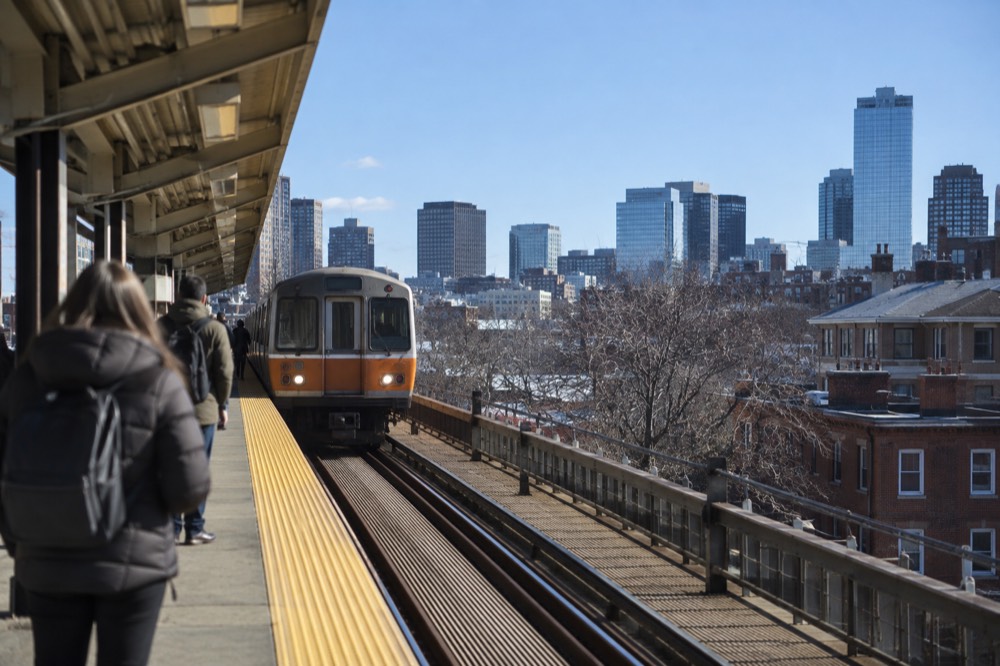 A train arriving at an elevated Orange Line station platform