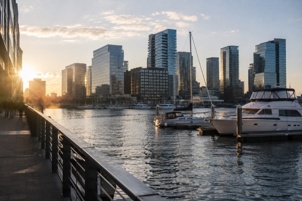Modern glass buildings of the Seaport District rising above Boston Harbor with boats in the foreground