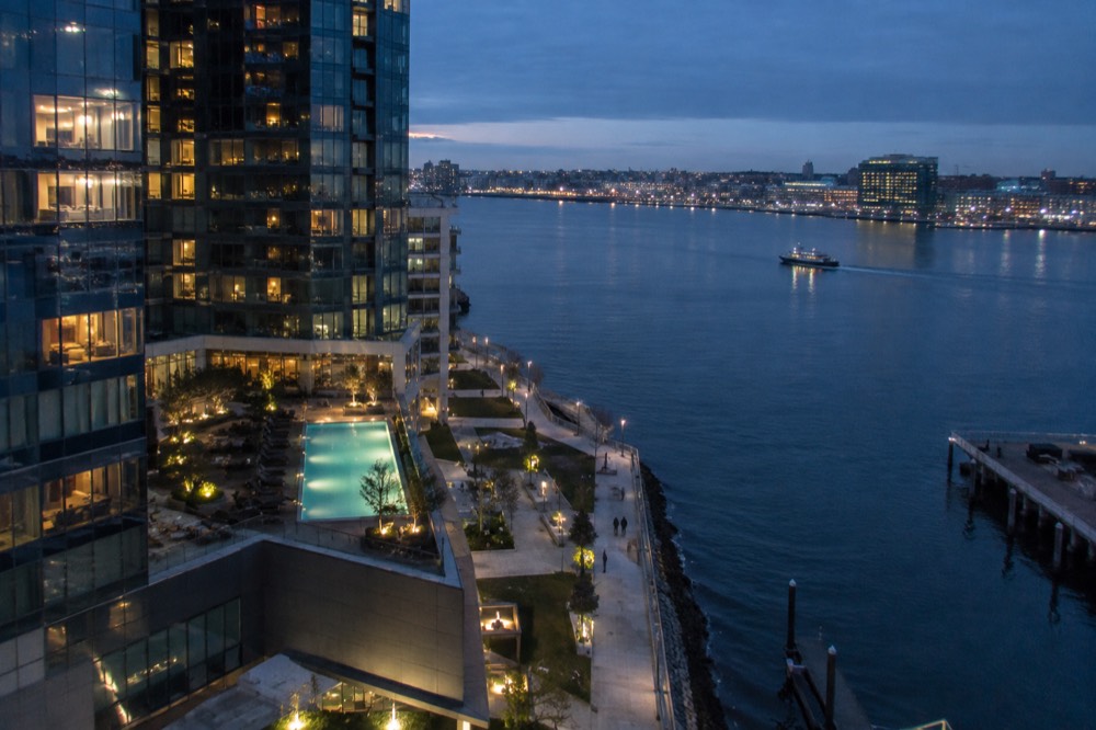 A modern hotel tower in the Seaport District at dusk with harbor lights reflected in the water