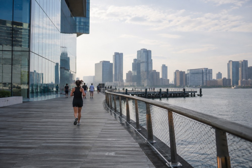 The contemporary glass facade of a harborfront art museum seen from a wooden boardwalk