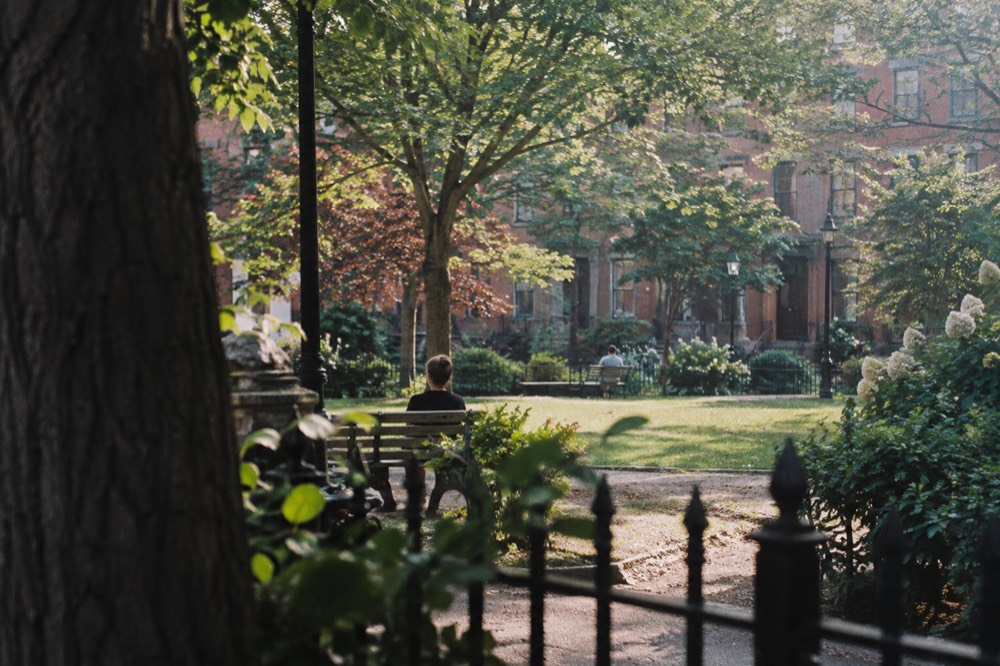 A small fenced park with benches surrounded by brick rowhouses in the South End