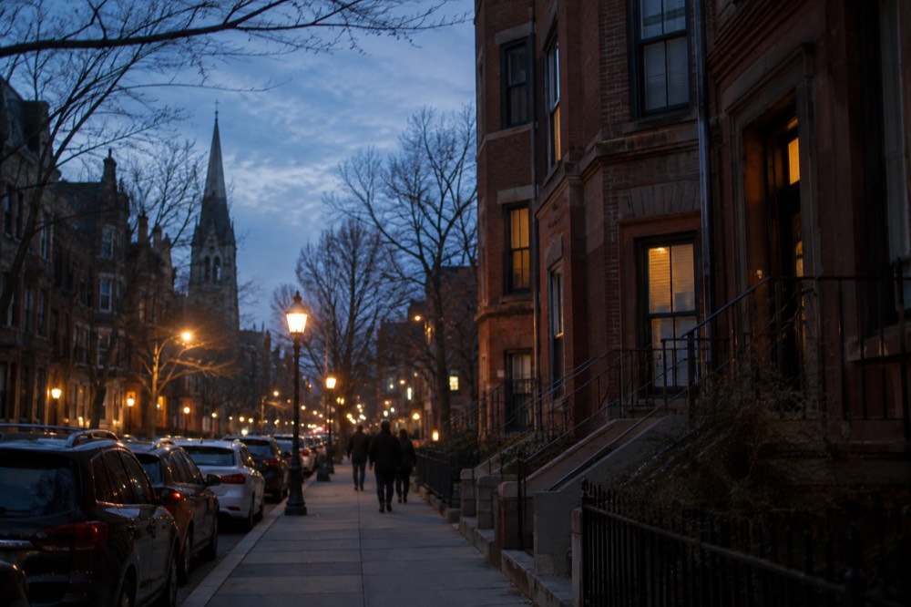 A Massachusetts Avenue street scene with brick buildings and a church spire in the distance