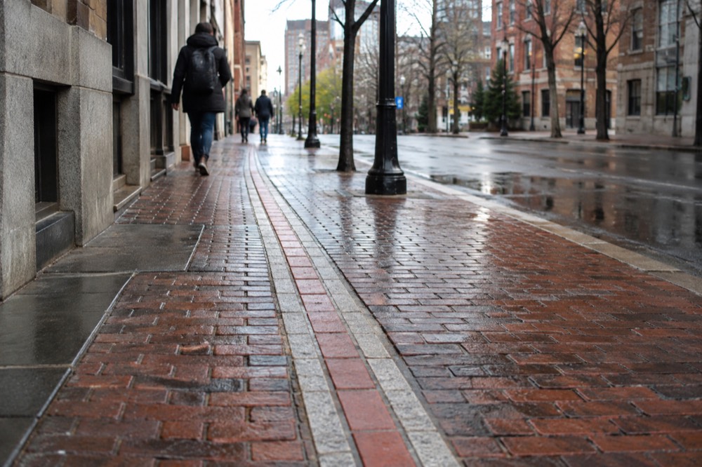 A red-lined Freedom Trail marker embedded in a brick Boston sidewalk