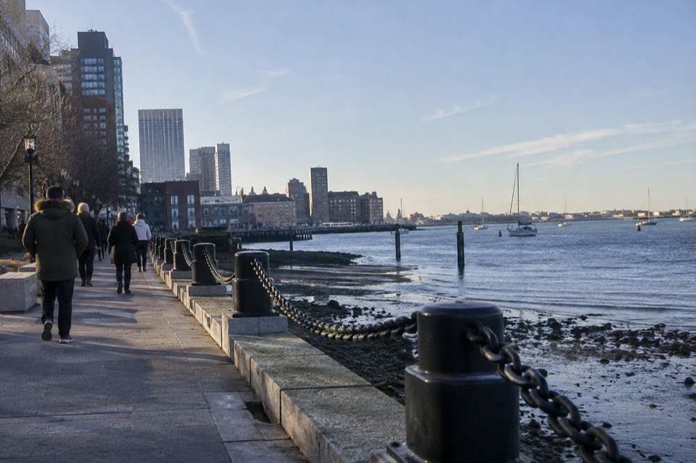 Visitors walking the Harborwalk path along Boston harbor at low tide