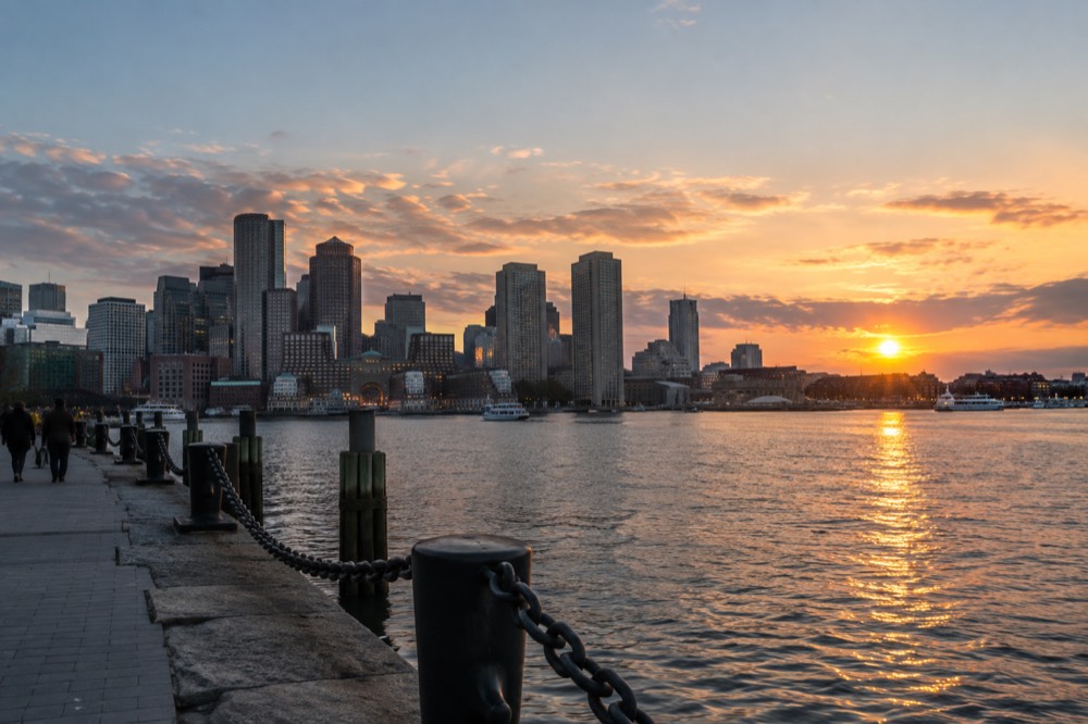 The Boston skyline seen across the harbor water at sunset from the waterfront