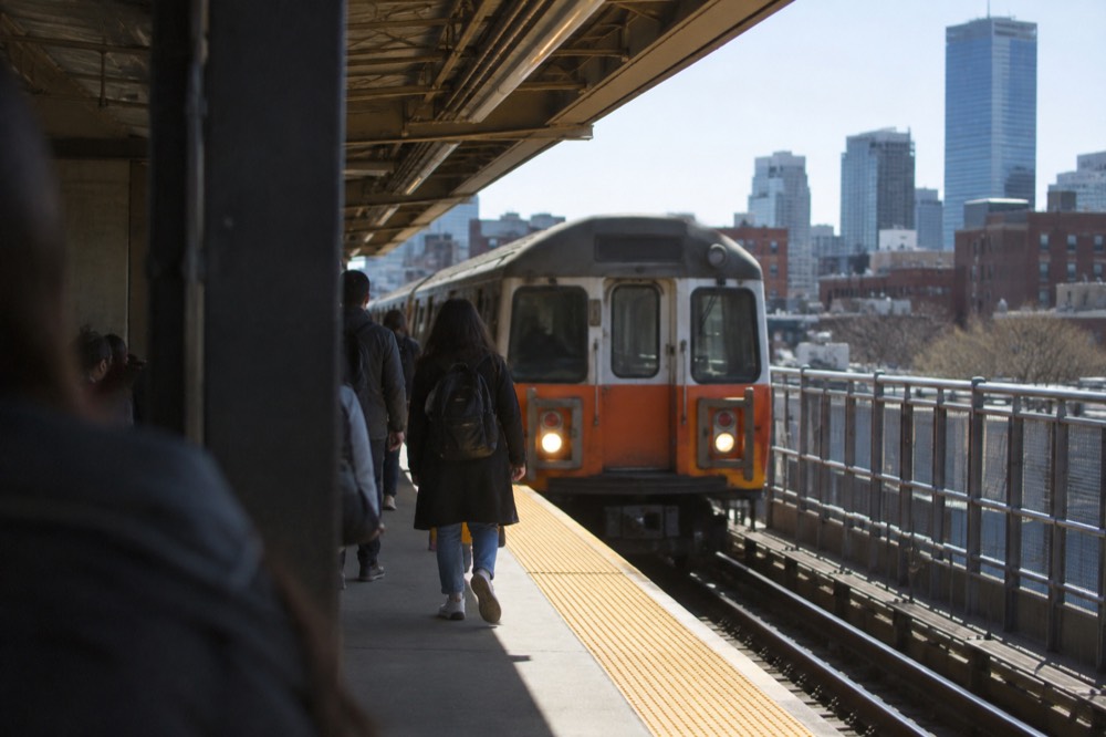 Subway platform with an Orange Line train arriving at an above-ground station
