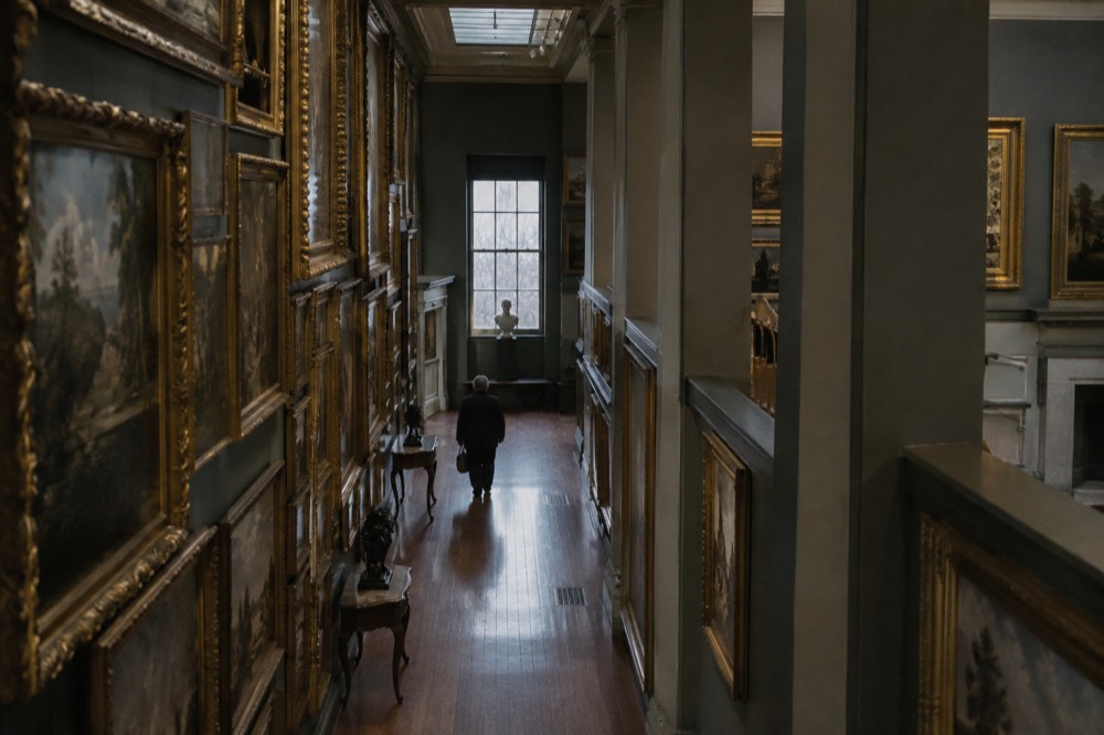 A gallery corridor in the Boston Athenaeum with paintings in gilt frames hung floor to ceiling