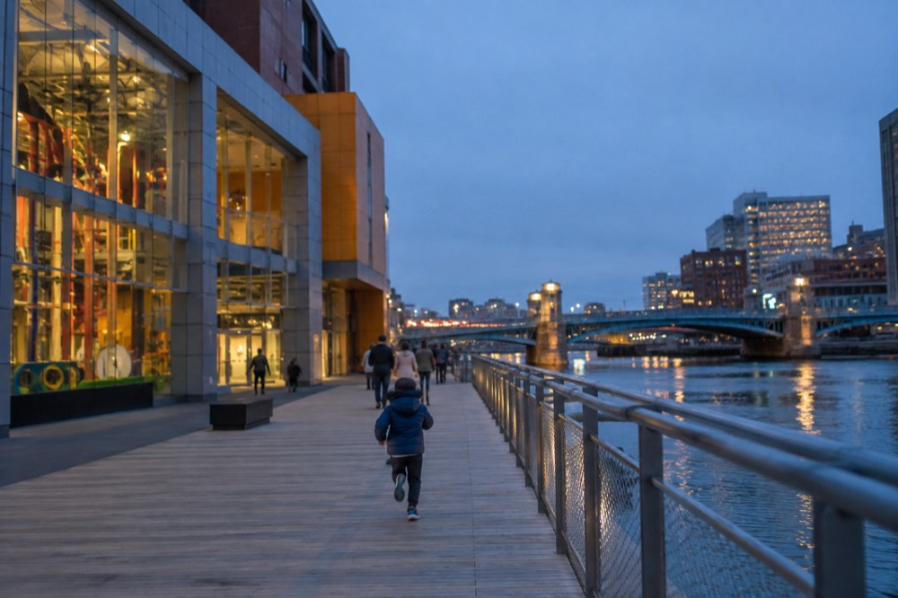 Colorful hands-on museum building beside a city waterfront channel with a bridge in the background