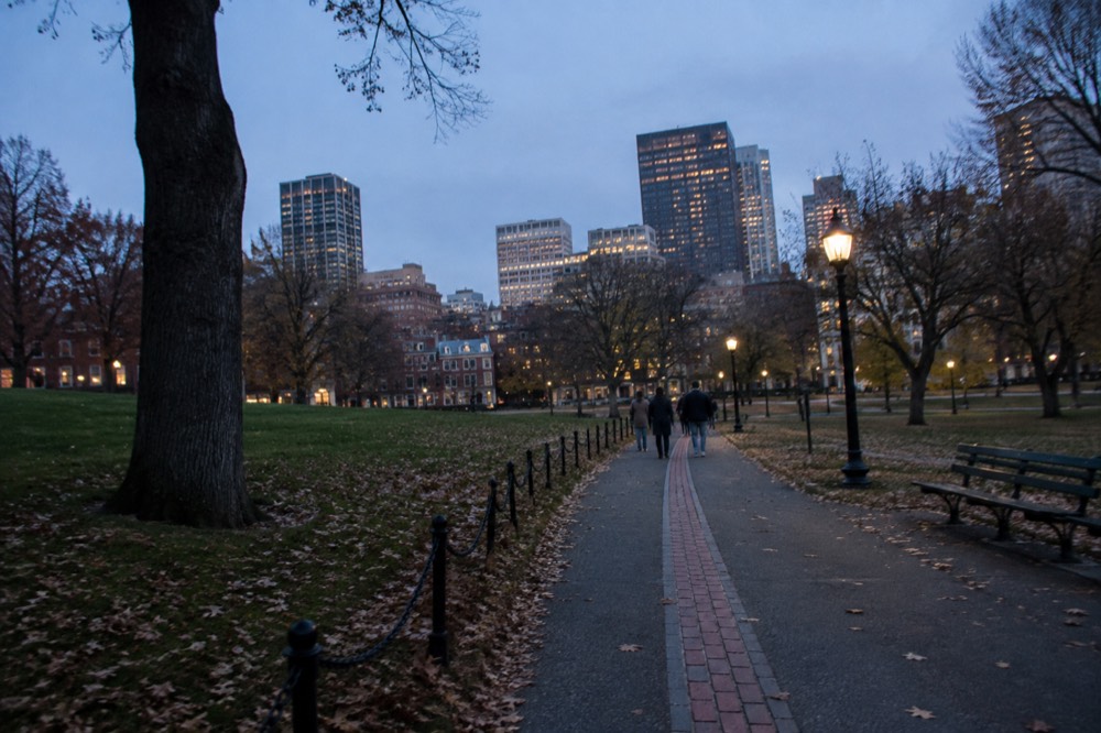 Red brick path marking the Freedom Trail through a green park with visitors walking
