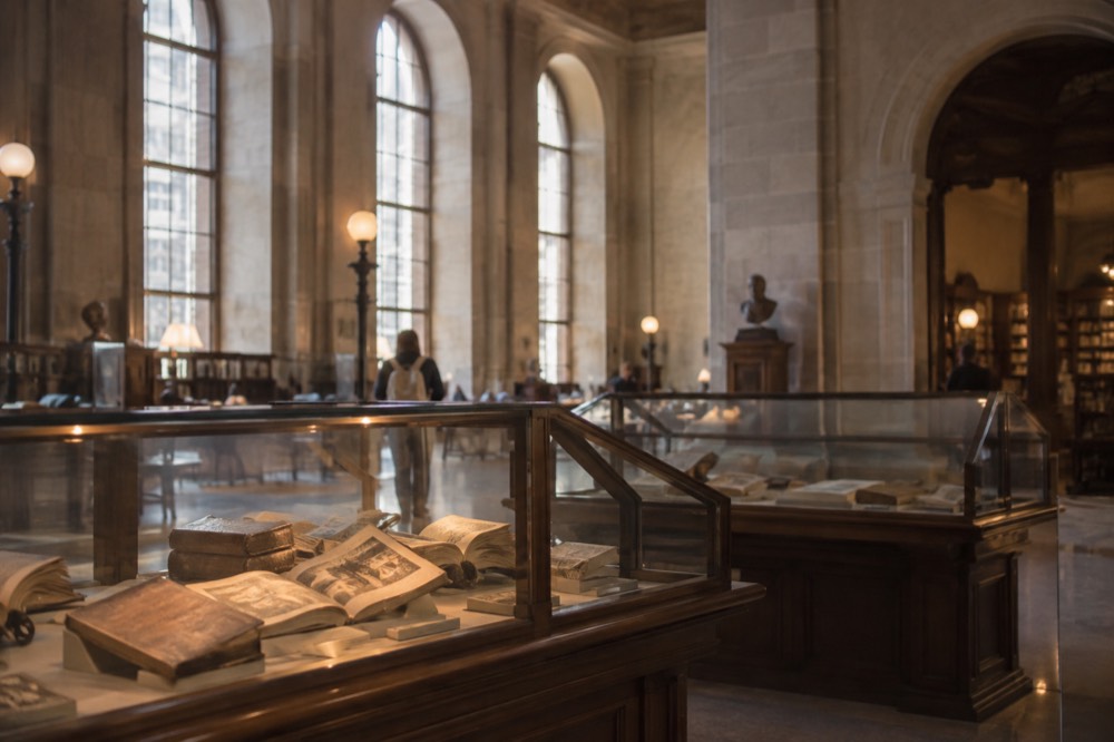 Display cases of old maps and atlases in a gallery with warm lighting