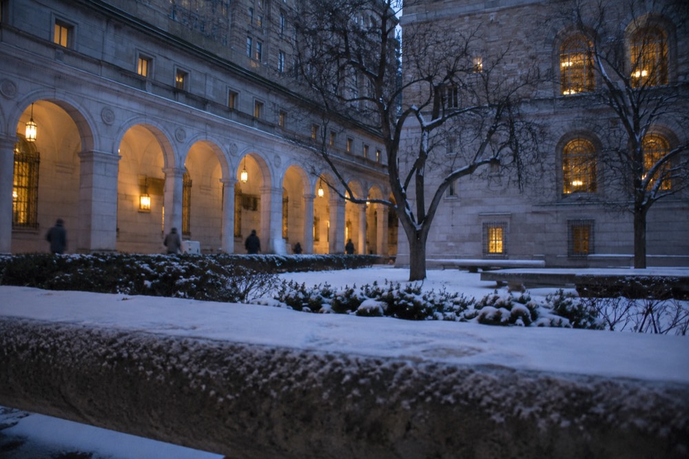 Stone arcade with snow on a courtyard and warm light through arches